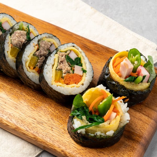Sushi Ko Bainbridge's tuna and vegetable sushi rolls, with two standing upright, on a wooden board.