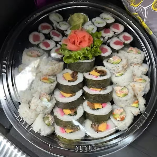 A large platter of assorted sushi rolls, including tuna, California, and tamago, with ginger and wasabi.