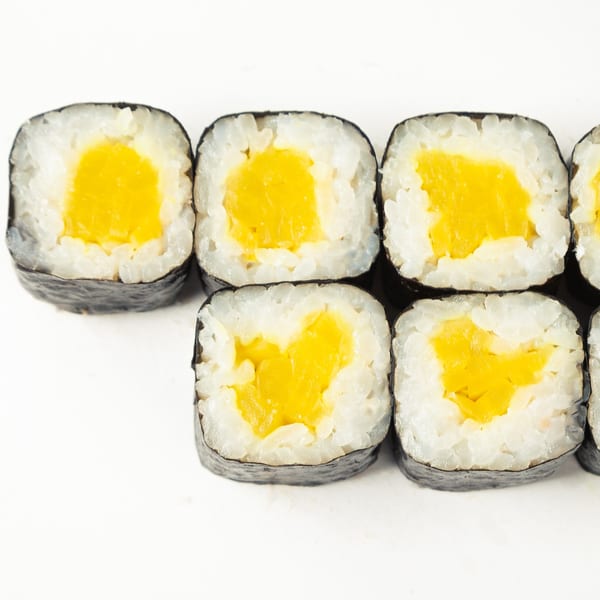 Close-up of six pieces of Sushi-Ko Bainbridge sushi with yellow filling and white rice.